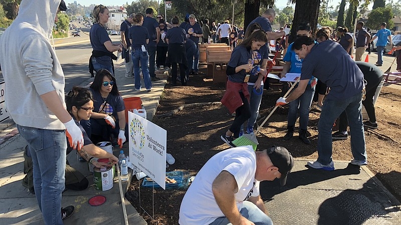 Volunteers work to pick up trash, build benches and paint near 50th Street and University Avenue in City Heights.